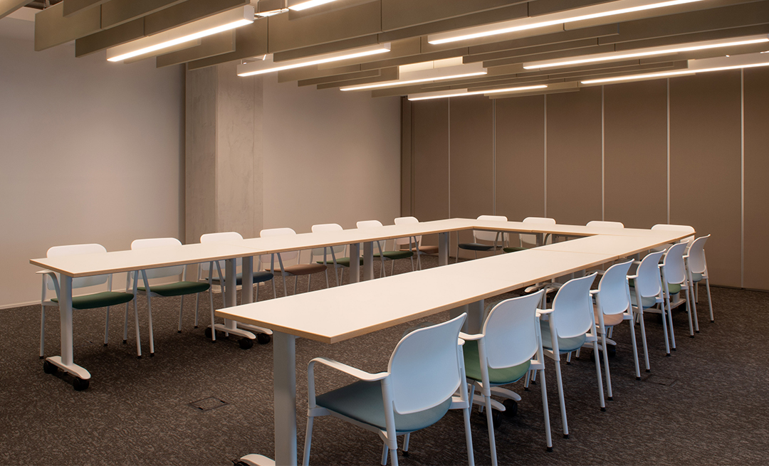 Sala de treinamento com mesas brancas e cadeiras
