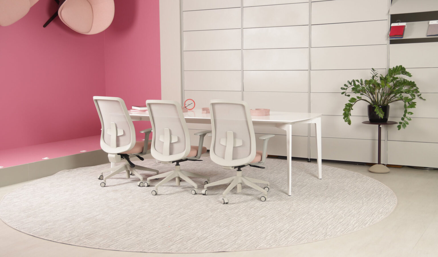 Sala de reunião com mesa branca e cadeiras ergonômicas